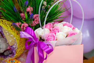 Festive background of a bouquet of roses, greenery and colorful balloons