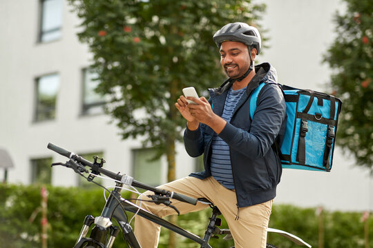 food shipping, profession and people concept - happy smiling delivery man with thermal insulated bag, smartphone and bicycle on city street