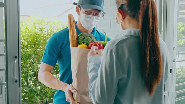 Food Delivery concept. Asian delivery man hand giving bag of food, fruit, vegetable delivery to costomer grocery delivery service.