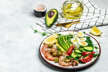 shrimps, prawns, soft fried egg, fresh salad, tomatoes, cucumbers and avocado on a light background. Ketogenic diet breakfast. Keto, paleo lunch. Top view