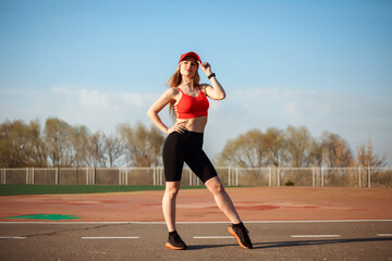 Full length portrait of athletic sportswoman posing at the sports ground, stadium in spring. 