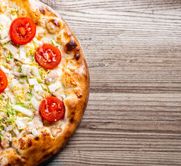 Pizza Caesar with chicken, cheese and tomatoes. Italian pizza on wooden table background © pavel siamionov