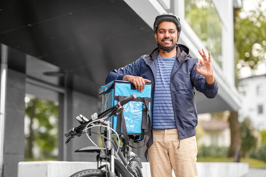 food shipping, profession and people concept - happy smiling delivery man with thermal insulated bag and bicycle on city street showing ok gesture
