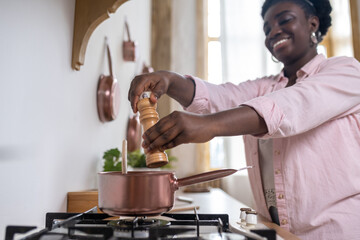 Plus size african woman in pink clothes cooking in the kitchen