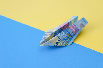 Paper plane from euro banknotes on a blue-yellow background