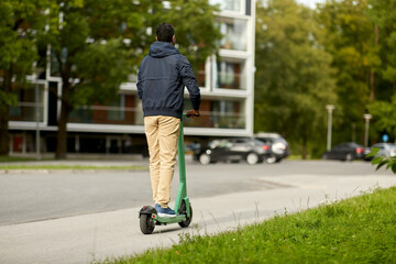 transport, safety and people and concept - young man riding electric scooter on city street © Syda Productions