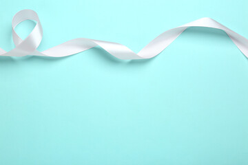 Beautiful white ribbon on light blue background, top view. Space for text