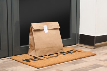 Paper bag on door mat near entrance indoors