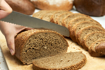 Woman hand slicing bread on cutting board