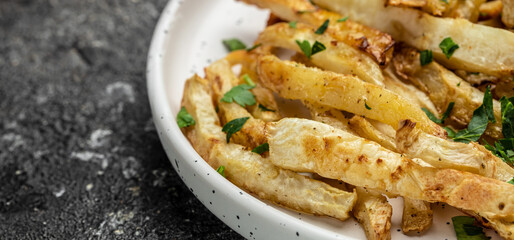 Oven roasted parsnips side dish on plate. Delicious vegetarian breakfast or snack, Clean eating, dieting, vegan food concept. Long banner format. top view