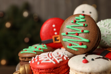 Beautifully decorated Christmas macarons against blurred festive lights, closeup