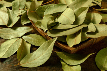 Bay leaves in a wooden bowl on a rustic background, a close-up