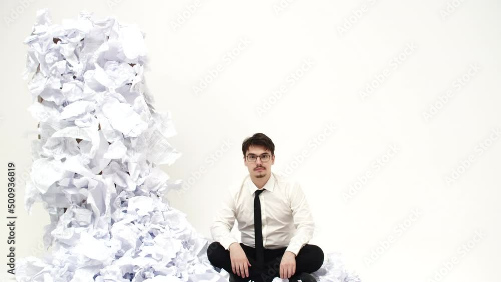 Poster man is sitting next to pile of crumpled documents and spreads hands to sides, front view. office wor