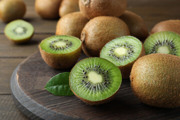 Cut and whole fresh ripe kiwis on wooden board, closeup