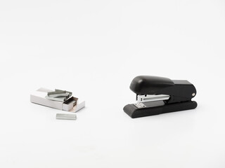 The black office stapler with paper clips container on the white background
