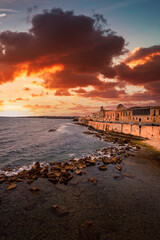 Spectacular red sunset on the sea with Maniace castle in Ortigia