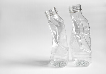 Side view of two crushed plastic bottles prepared for recycle on a light background. Waste sorting and plastic recycle concept