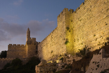 Twilight view of the landmark, stone Tower of David minaret as seen through branches and leaves of trees along the golden sunset walls of the Old City of Jerusalem. © Yehoshua Halevi