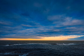 Sunset over the sea with cloudy sky and sun glow in the background