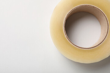 Roll of adhesive tape on light background, top view. Space for text