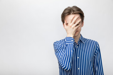 Young man doing facepalm studio shot on gray background
