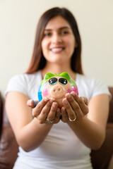 young latin woman showing her piggy with her savings