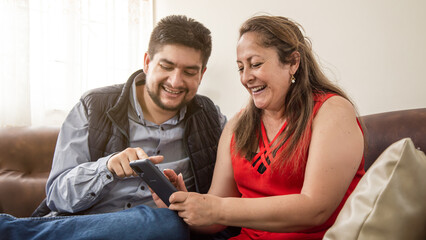 latin mother and son looking at cell phone happy