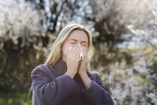 a teenage girl blows her nose into a handkerchief and sneezes. Spring allergy to flowering. Symptoms of the disease