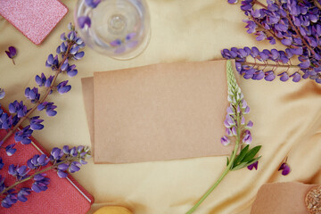 Craft paper natural mock up. Lupins purple flowers, wine glass decorations. Summer invitation, birthday card, Mother's day concept. Feminine vibrant background. Wellness closeness to nature concept