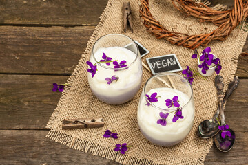 Vegan panna cotta dessert with fresh violet flower. Striped very peri color food, rustic style