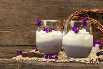 Vegan panna cotta dessert with fresh violet flower. Striped very peri color food, rustic style