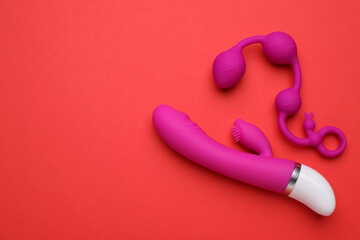 Pink sex toys on red background, flat lay. Space for text