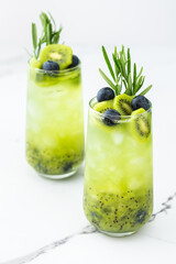 Refreshing drink with kiwi smoothie, summer sweet fruit juice with blueberries and rosemary