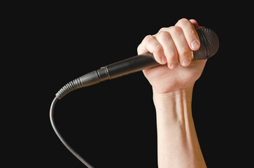 Microphone in hand closeup. Isolated on a black background