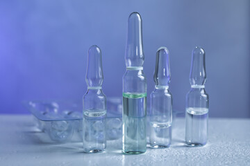 Pharmaceutical ampoules with medication on white table against color background
