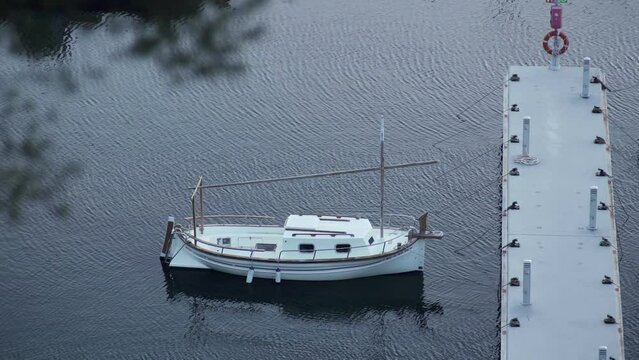 Boats stand at the pier in the port. Small white yachts on dark water. Cloudy day at the boathouse. Sea transport. Marina. The small port in a fishing village. Holidays on the coast. Water ripple.