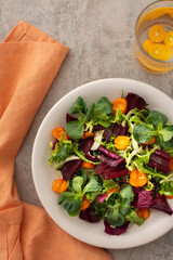 Warm salad with mixed salad with boiled carrots and beetroot with spices, water with kumquat