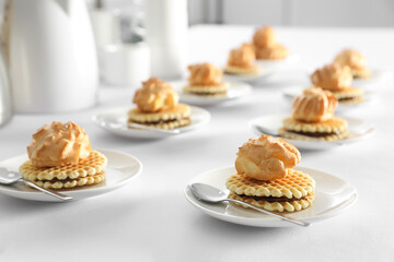Many delicious waffles with cream served on white table for coffee break