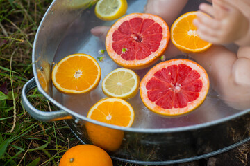 closeup of an iron bath with orange and grapefruit slices with a baby sitting in it