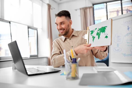 distance education, school and remote job concept - happy smiling male geography teacher with world map and laptop computer having online geography class at home office