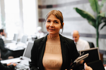 Portrait of smiling businesswoman holding documents at law office