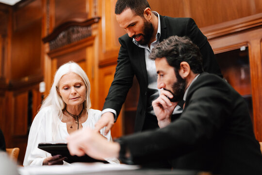 Male and female financial advisors brainstorming over document in meeting at office