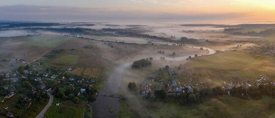 Panoramic aerial view of foggy Moscow river on summer sunrise. Mozhaysk, Moscow Oblast, Russia.