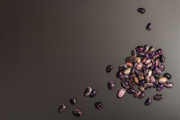 Assorted multicolored beans scattered on black stone background
