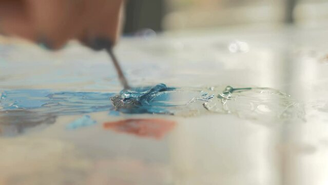 Artist mixing acrylic paint using palette knife. Real-Time
