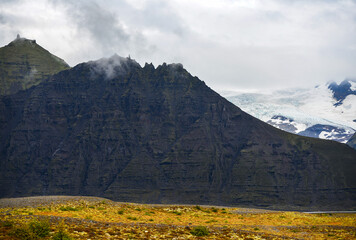 A partial view of Svinafellsjokull glacier behind a mountain ridge, as seen from the Route 1, or Ring Road, near Skaftafell, Vatnajokull National Park, South Iceland