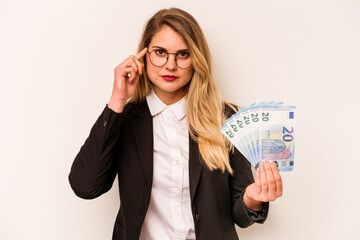 Young business caucasian woman holding a banknotes isolated on white background pointing temple with finger, thinking, focused on a task.