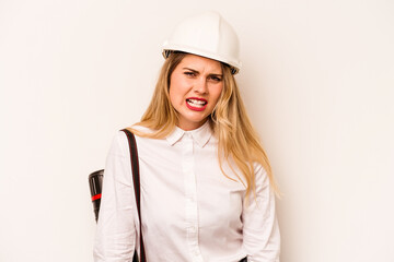 Young architect woman with helmet and holding blueprints isolated on white background screaming very angry and aggressive.