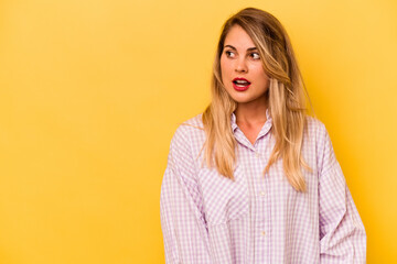 Young caucasian woman isolated on yellow background being shocked because of something she has seen.