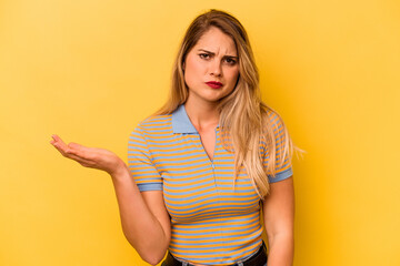 Young caucasian woman isolated on yellow background doubting and shrugging shoulders in questioning gesture.